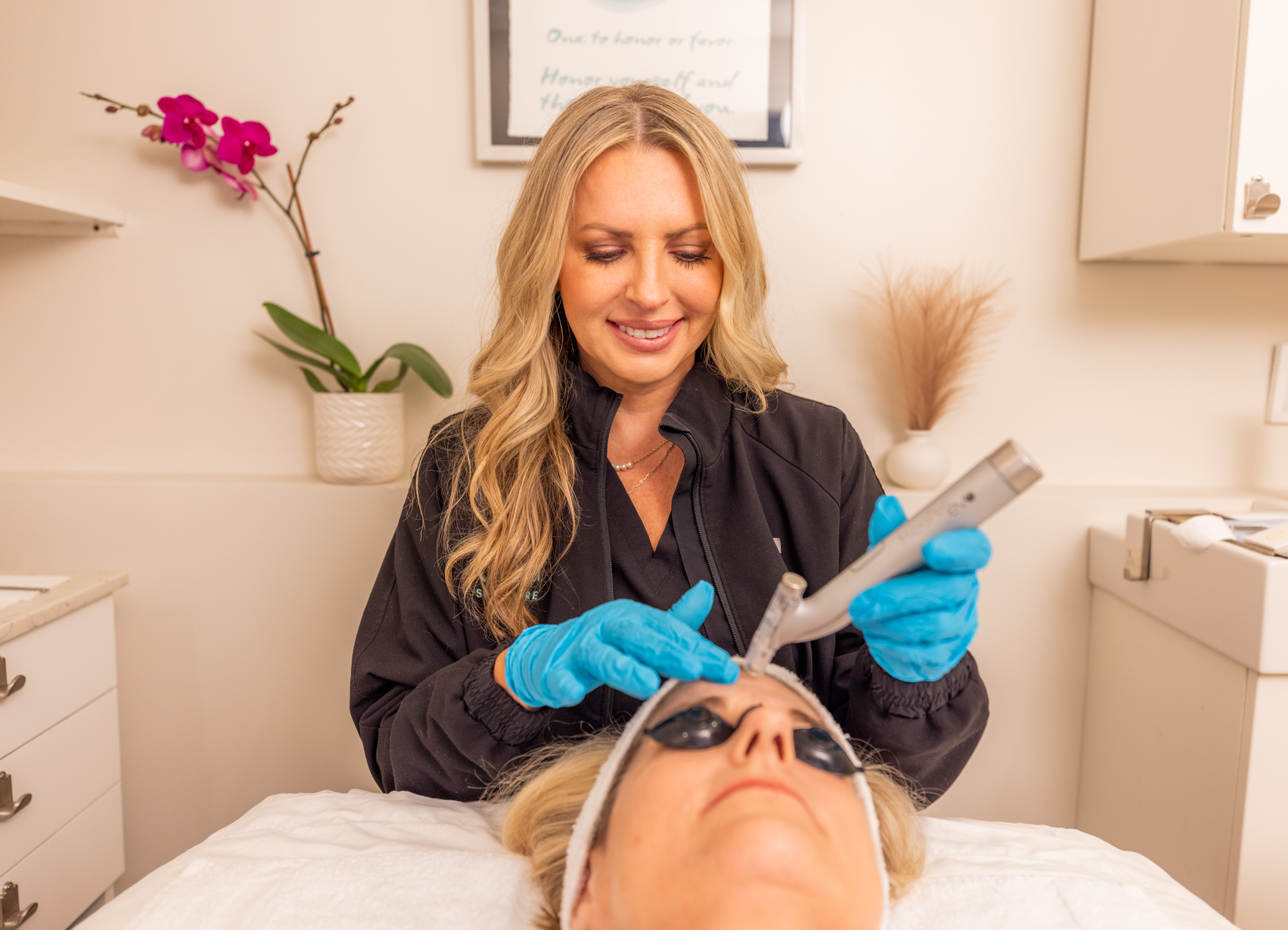 A woman performing microneedling on a womans forehead